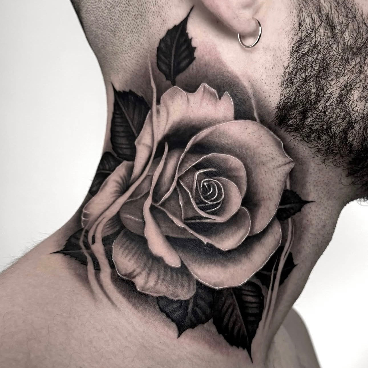 Tatuagem realista de rosa detalhada no pescoço, black and grey com sombreado suave, feita na Dilúvio Tattoo em Benfica, Lisboa.