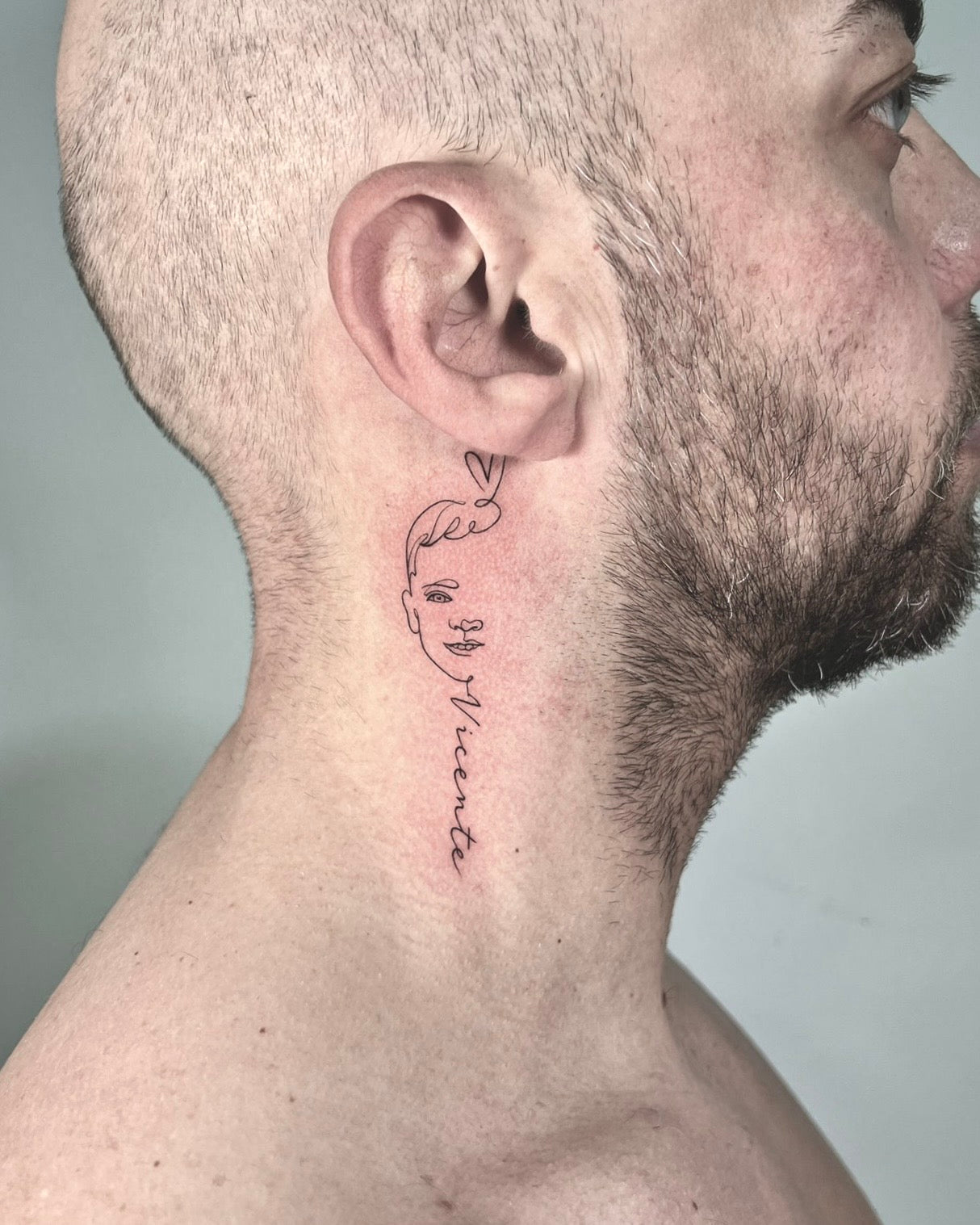 Tatuagem fine line de lettering cursivo com pequeno coração no pescoço, estilo dedicatória personalizada, no Dilúvio Tattoo em Benfica.