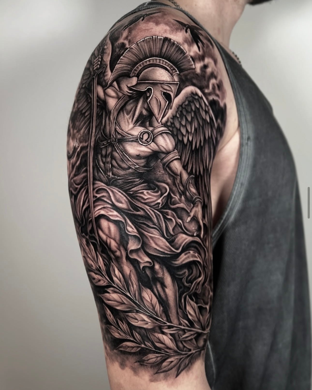tatuagem realista em black and grey de Arcanjo São Miguel com capacete e asas no braço, estilo religioso realismo, feita na Dilúvio Tattoo em Benfica, Lisboa.