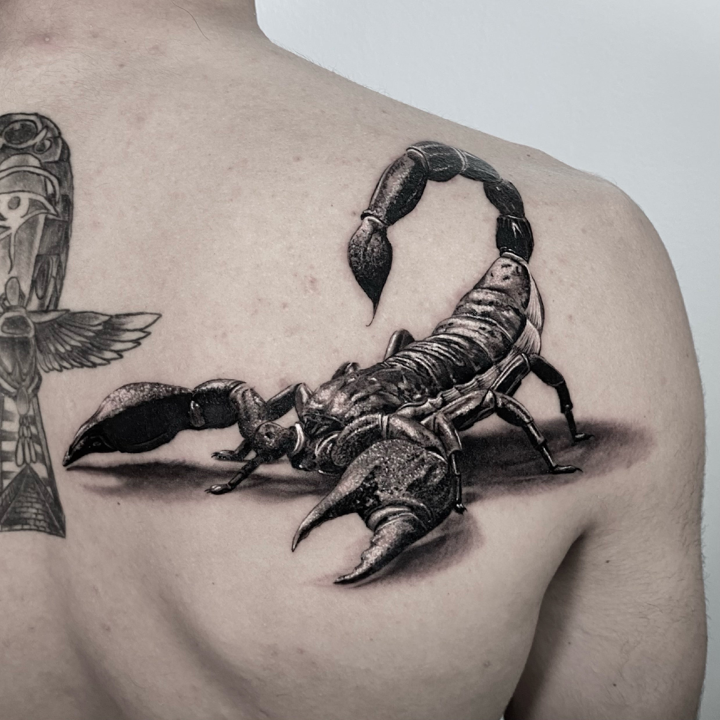 Tatuagem realista em black and grey de escorpião com hieróglifos egípcios nas costas, estilo realismo 3D, feita na Dilúvio Tattoo em Benfica, Lisboa