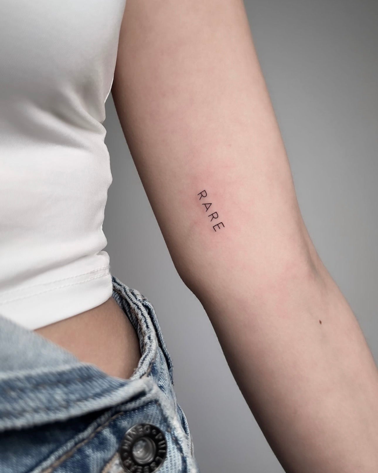 Tatuagem fine line minimalista com a palavra 
