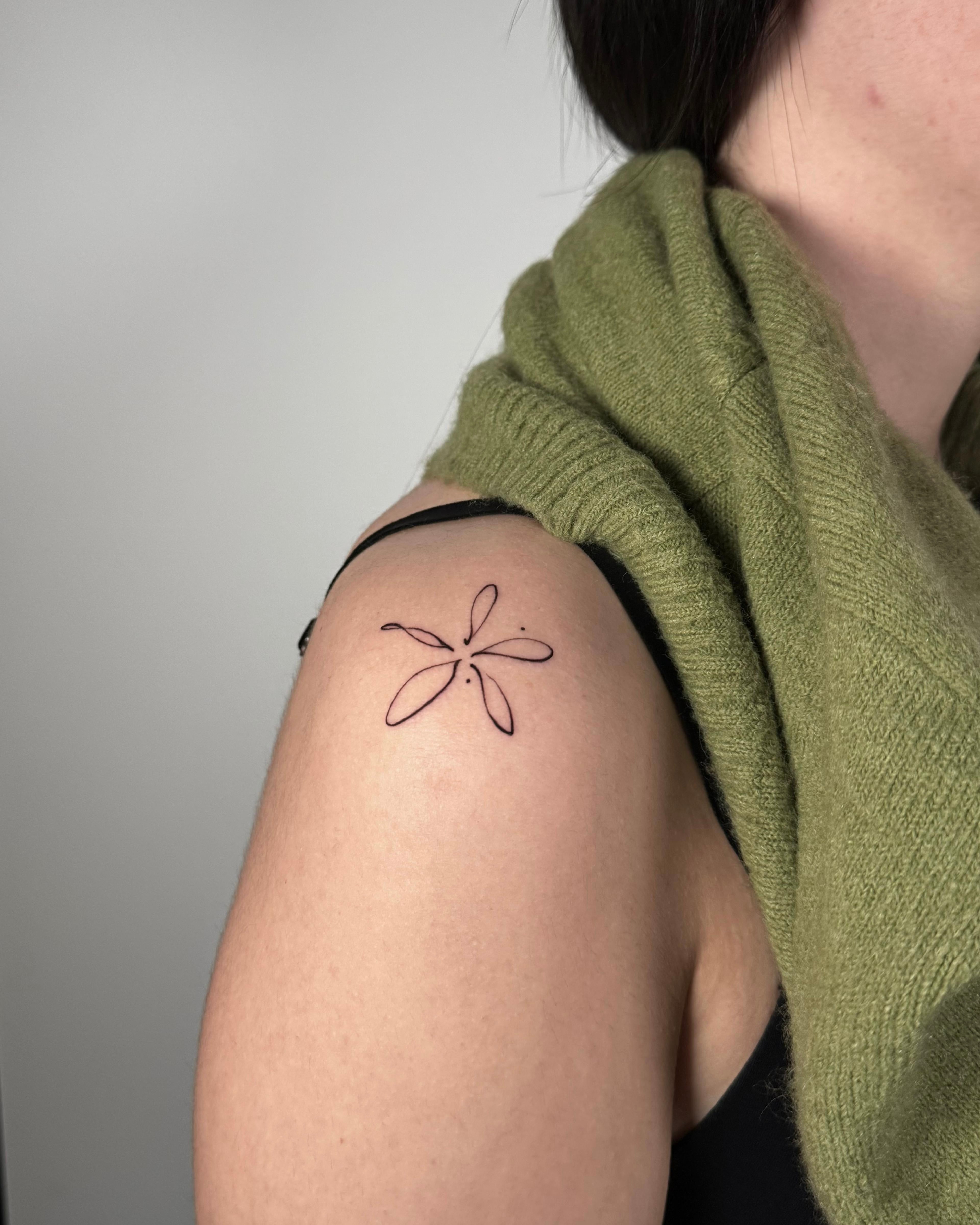Tatuagem fine line de libélula em traço contínuo no ombro, estilo minimalista feminino, no Dilúvio Tattoo em Benfica, Lisboa.