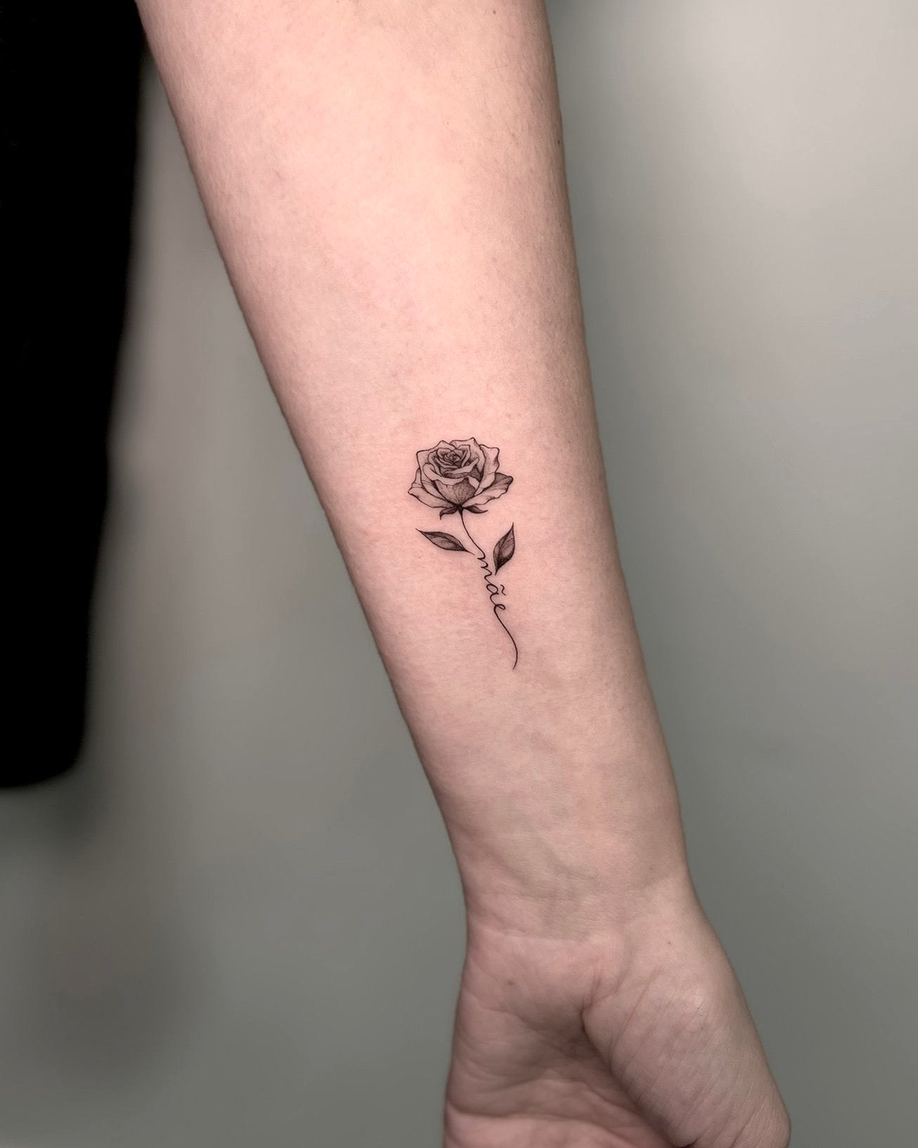 Tatuagem fine line de rosa pequena com pormenor delicado no braço, estilo minimalista floral, feita no Dilúvio Tattoo em Benfica, Lisboa