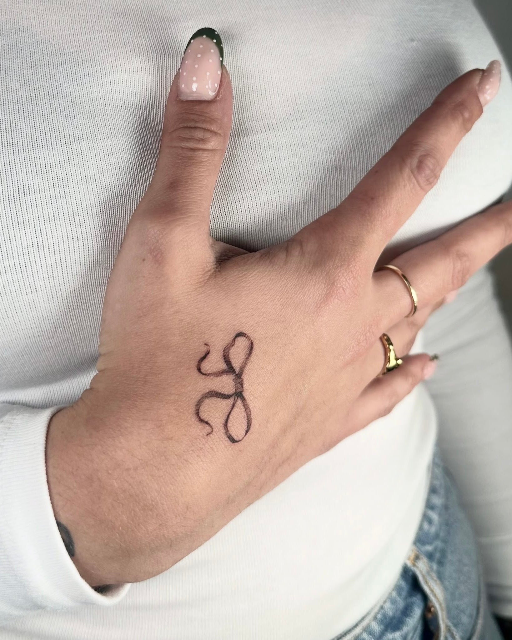 Tatuagem fine line do símbolo do zodíaco Leão na mão, estilo minimalista astrológico, no Dilúvio Tattoo em Benfica, Lisboa.