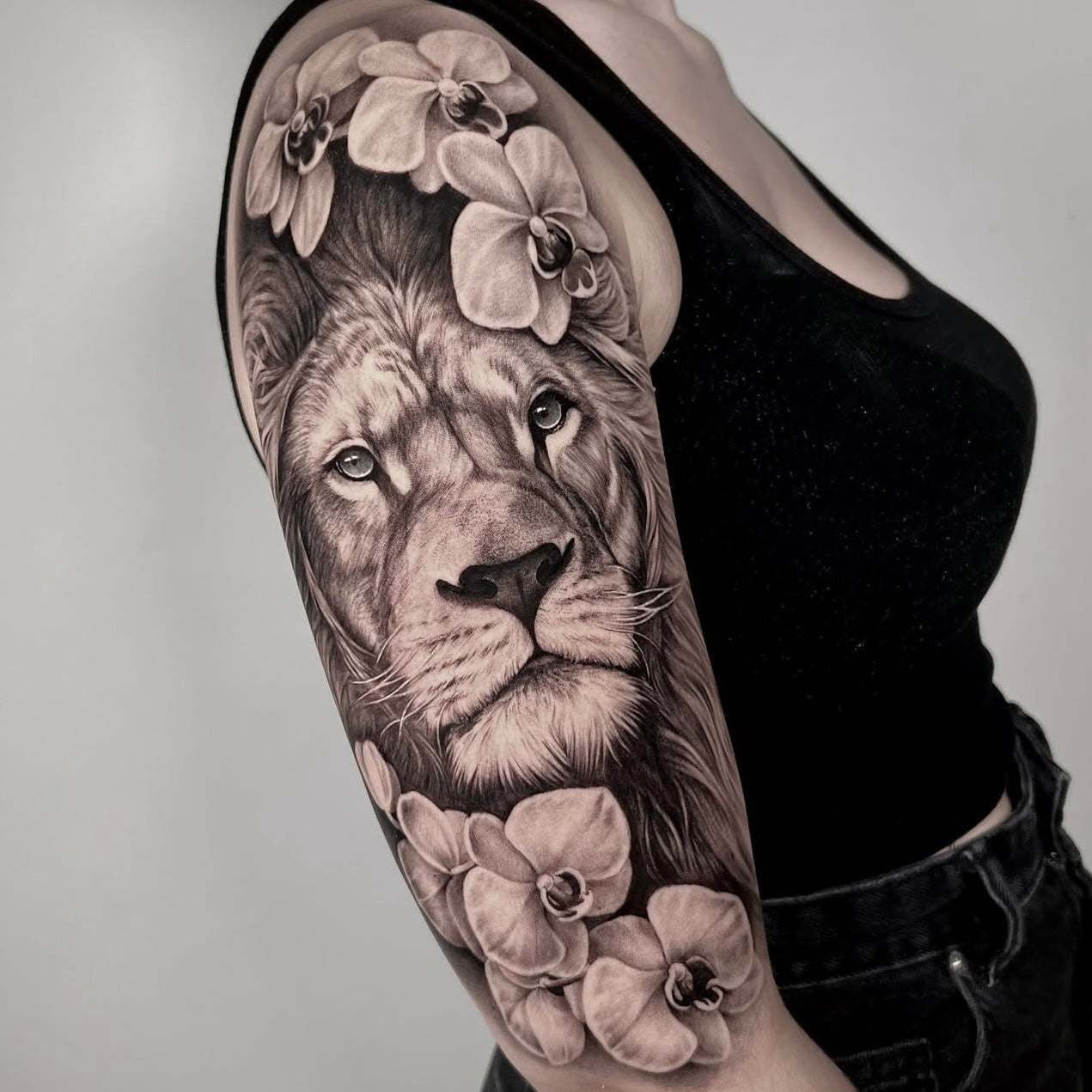 tatuagem de leão com orquídeas no braço, realismo black and grey | Dilúvio Tattoo Lisboa