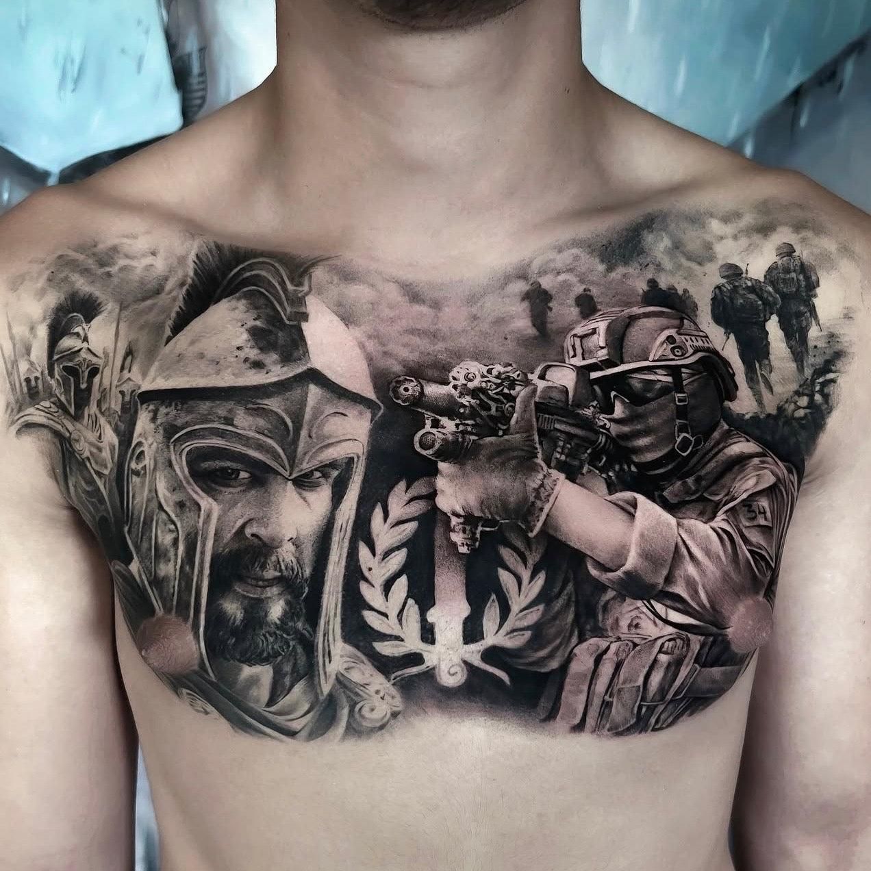 Tatuagem de peito em black and grey com composição de guerreiro espartano e soldado moderno em cena de batalha, estilo realismo militar, Dilúvio Tattoo Benfica.