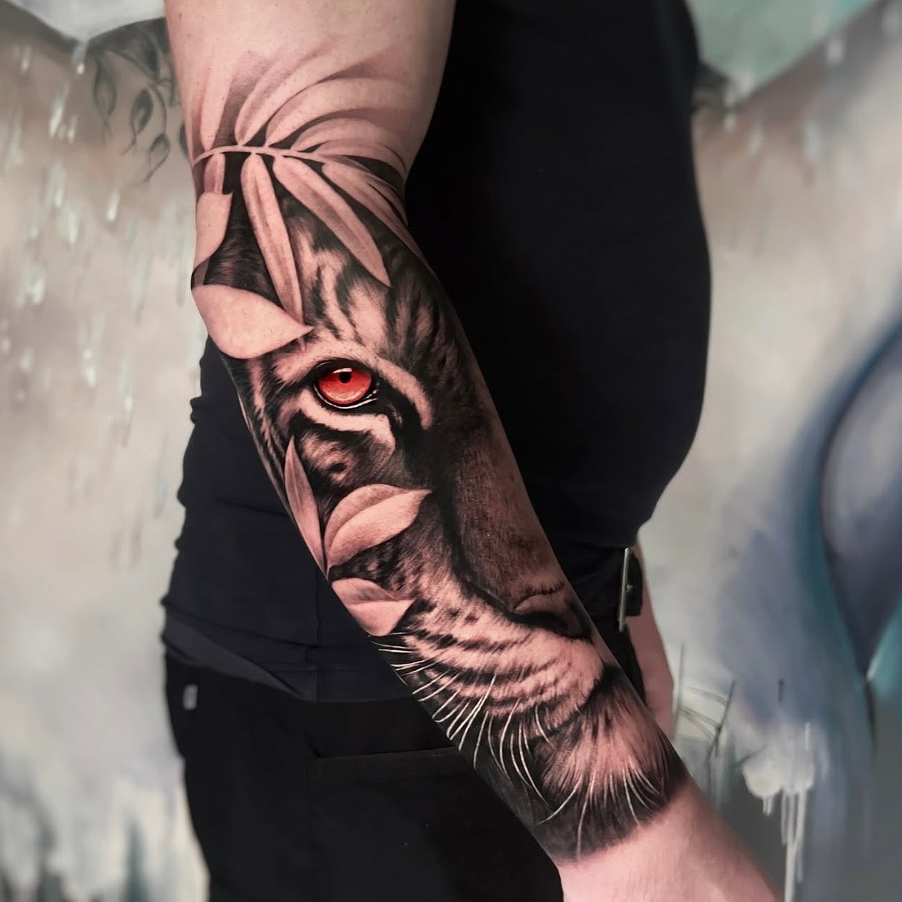 Tatuagem realista de tigre com detalhe do olho a vermelho no braço, black and grey com pop of color, feita no Dilúvio Tattoo em Benfica, Lisboa