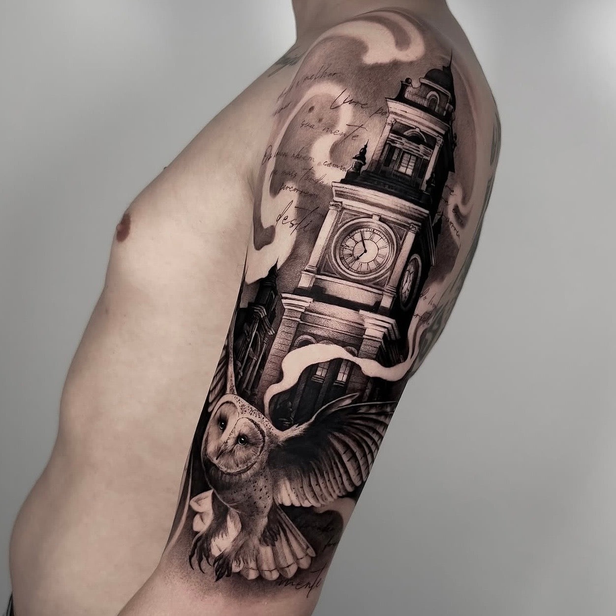Tatuagem realista em black and grey de torre do relógio com coruja em voo no braço, estilo arquitetónico realismo, feita na Dilúvio Tattoo em Benfica, Lisboa.